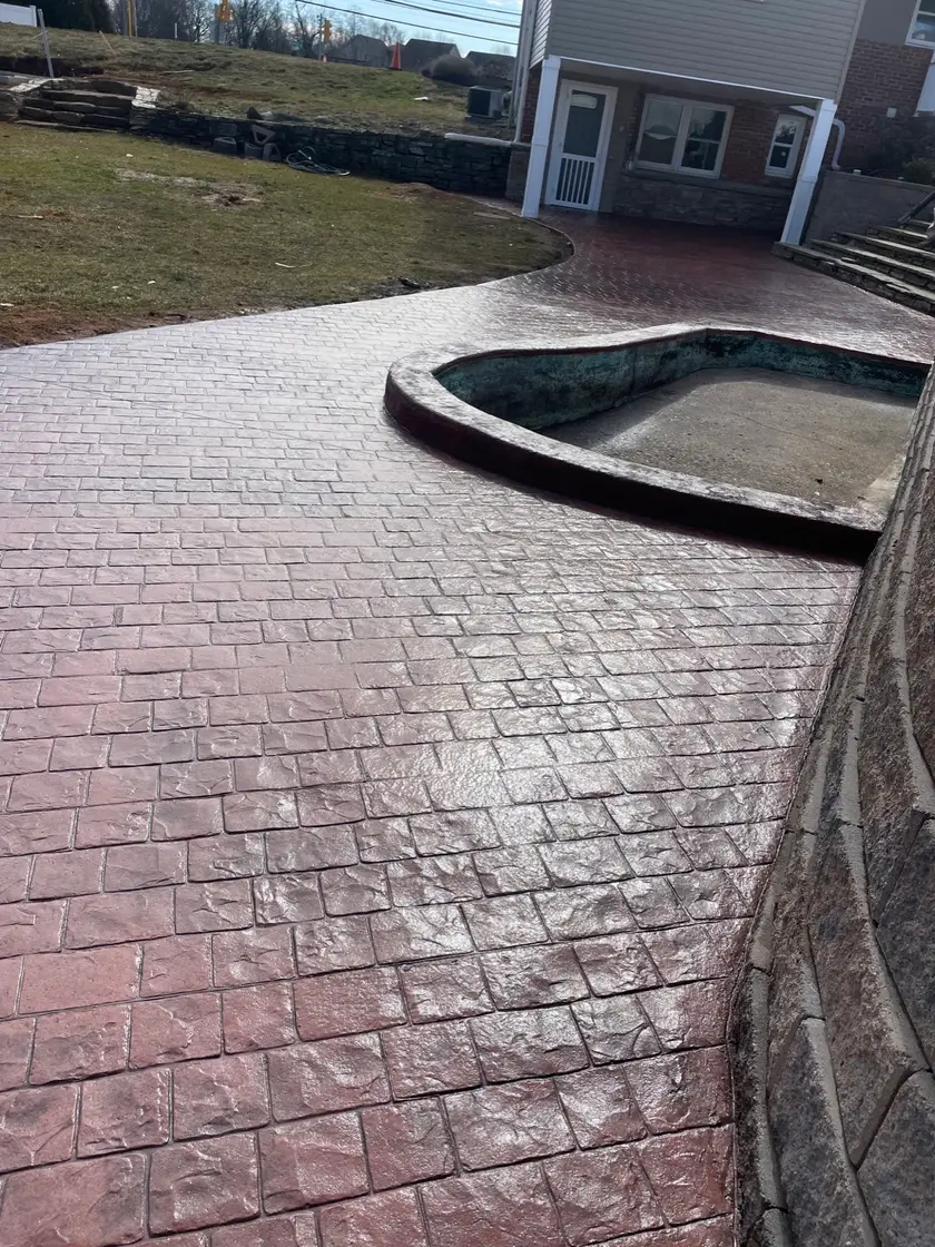 Burgundy stamped concrete driveway with retaining wall and pool